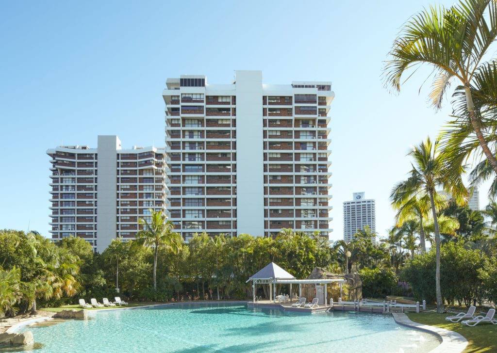 A professional photograph of a gold coast residential property's pool and outdoor area; with apartment complexes in the background.